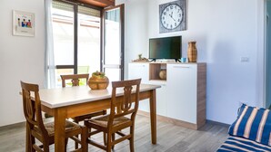 A dining area with a wooden table and chairs, a television, and a clock on the wall. - Villetta Myalea - Capilungo (Capilungo)