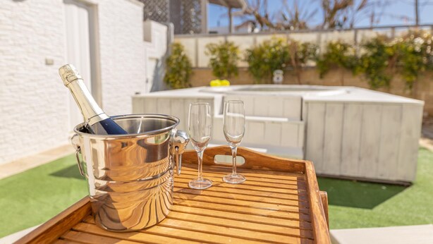 A hot tub, a wooden tray, and a champagne bucket with glasses on a patio. - Villetta Myalea - Capilungo (Capilungo)