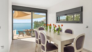 Un espace repas comprenant une table, des chaises et une vue sur la mer.