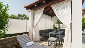 A covered outdoor seating area with a cushioned lounge chair, a small table, and a sofa. - Nice apartment in Srinjine (Srinjine)