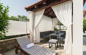 Relax in a serene outdoor seating area with a pergola, lounge chair, and sofa.
