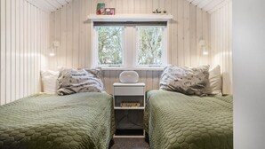 A cozy room with two beds, a small table, and a window with a view of trees. - 3 bedroom stunning home in Ringkøbing (Ringkøbing)