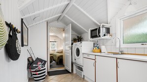 A compact kitchen with a washing machine, a microwave, and a sink. - 3 bedroom stunning home in Ringkøbing (Ringkøbing)