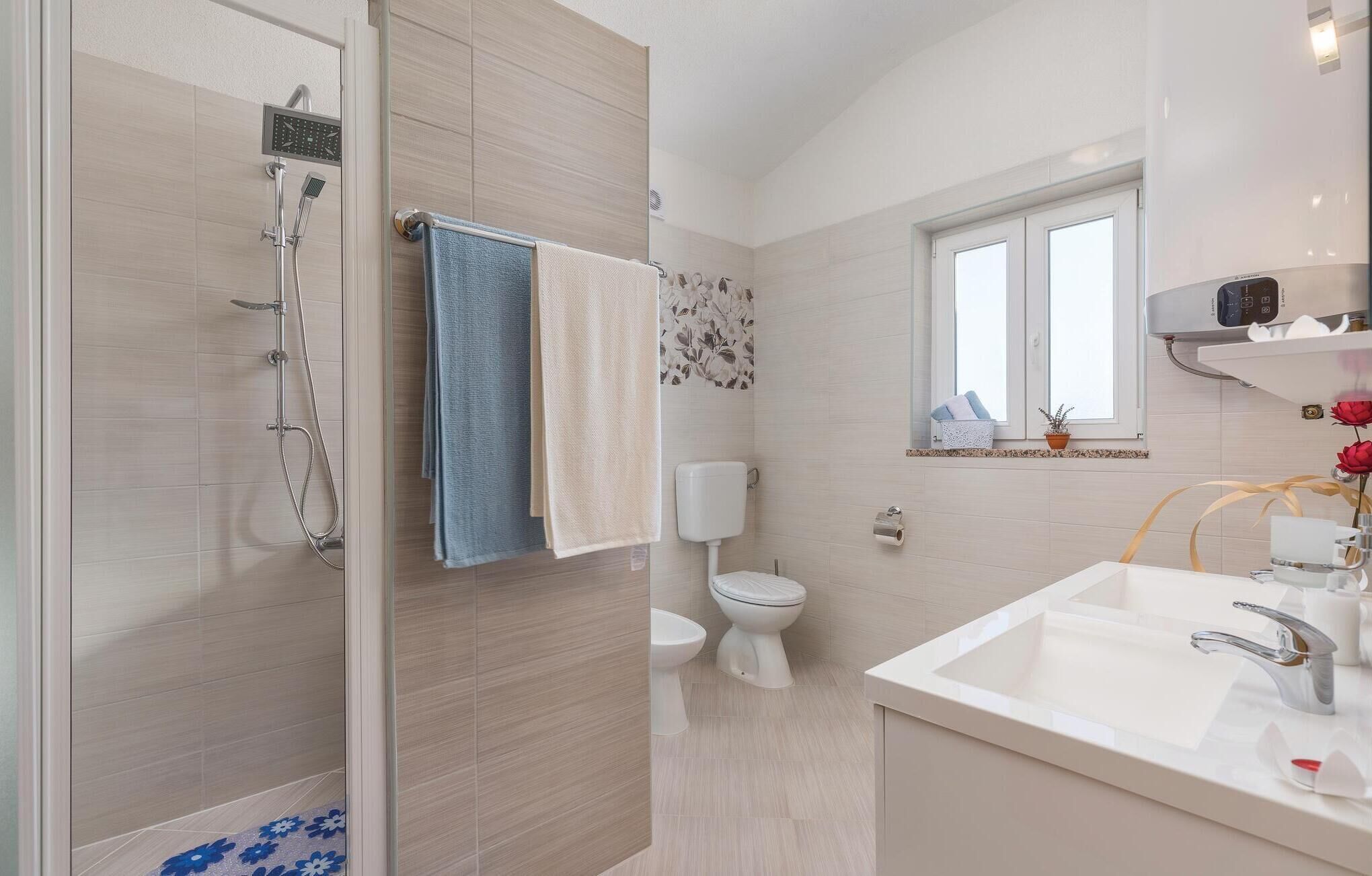 A modern bathroom with a shower, toilet, and sink.