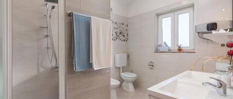 A modern bathroom with a shower, toilet, and sink.