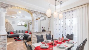 Comedor con mesa blanca para cuatro, sillas negras y camino de mesa rojo.