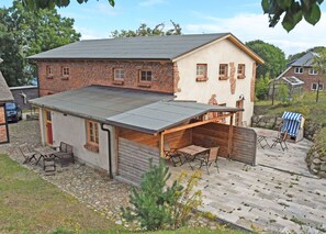 A two-story house with a covered patio, stone pathway, and a small garden area. - 06 Holiday apartment Bauernrose with lake view - Haus am Höft in Gager with lake view (Gager)