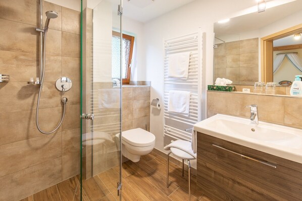A modern bathroom with a glass shower enclosure, a toilet, a sink with a vanity, and a towel rack.