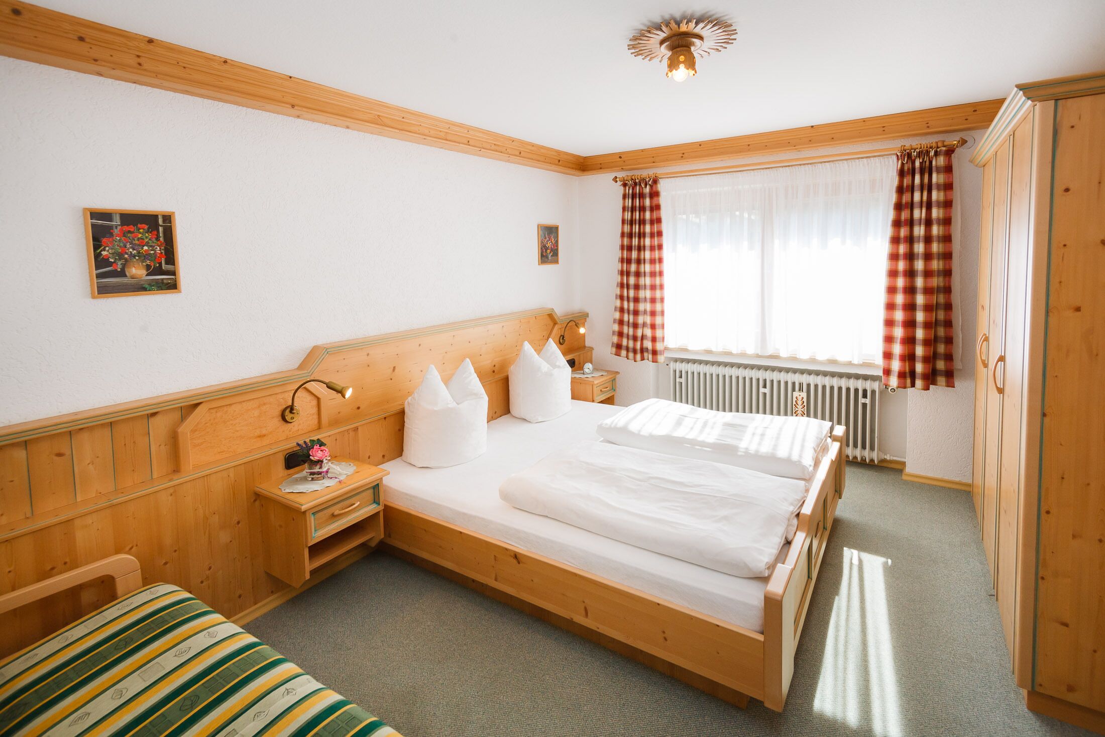 Ein Schlafzimmer aus Holz mit einem Einzelbett, einem Nachttisch und einem Fenster mit Vorhängen.