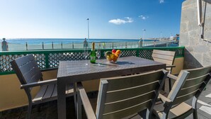 Una mesa con sillas y un cuenco de fruta, con vista a la playa.