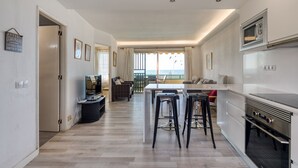 Cocina moderna con una isla central, taburetes de bar y un comedor con vistas.