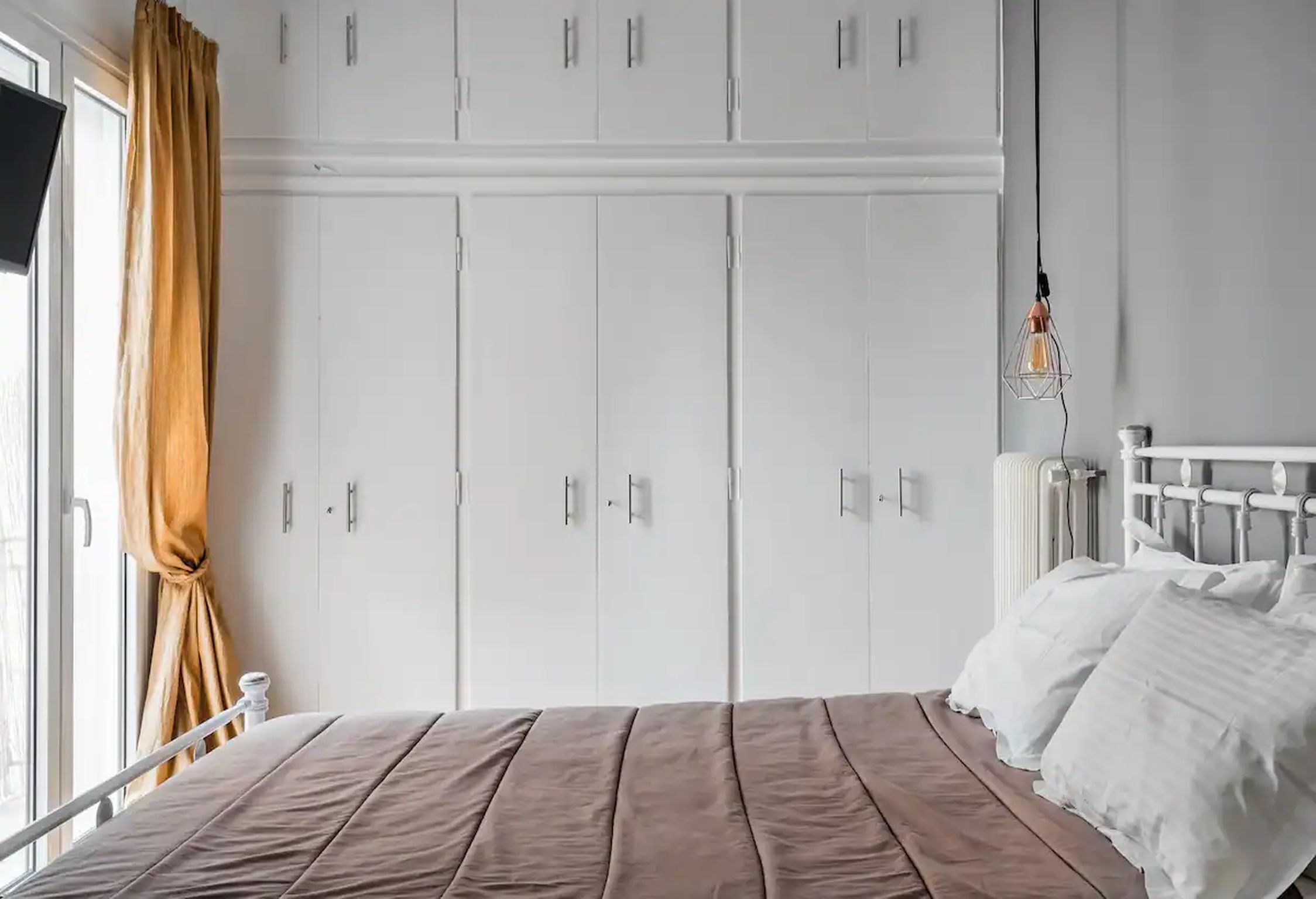 A bedroom with a bed, white wardrobe, and a radiator.