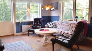 A cozy living room with a leather armchair, a tufted sofa, a round coffee table, and a pendant light. - 3 bedroom stunning home in Slite (Slite)