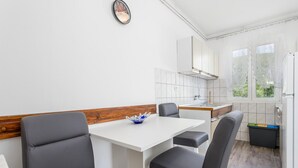 A compact kitchen with a white countertop, a sink, and a window. There are two black chairs and a white table with a blue decorative bowl. - 1 bedroom amazing apartment in Rab (Rab)