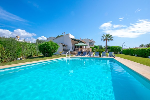 A swimming pool with lounge chairs and a building in the background.