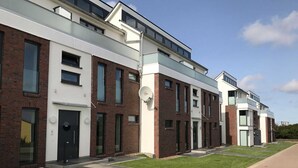 Een modern appartementencomplex met bakstenen gevel, grote ramen en een plat dak.