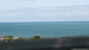 Uitzicht op de kust met een waterlichaam, windturbines en een verre oever.