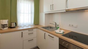 A compact kitchen with a sink, stove, and cabinets.