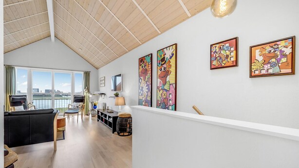 A spacious living area with a high ceiling, large windows, and a view of the city.