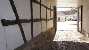 A narrow cobblestone alleyway with a white wall featuring dark timber framing. - Apartment on the market square (Biesenthal)