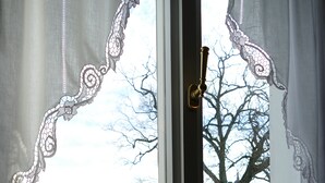 A window with a view of a building and a tree. - Apartment on the market square (Biesenthal)