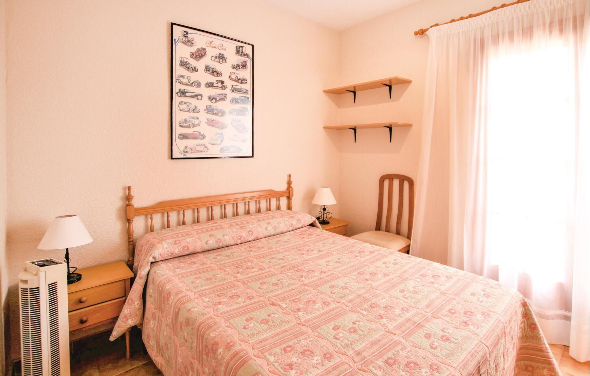 A bedroom with a bed, two bedside tables, a chair, a wall-mounted shelf, and a radiator.
