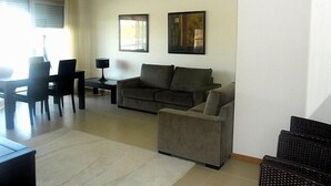 Ein Wohnzimmer mit Sofa, Sesseln und einem Essbereich mit Stühlen und Tisch.