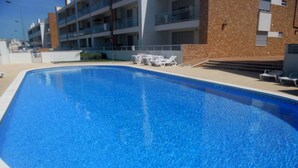 Ein rechteckiger Pool mit klarem, blauem Wasser, umgeben von einer weißen Poolterrasse.