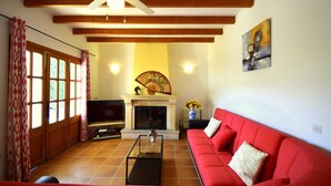 Un salon avec un canapé rouge, une cheminée, un téléviseur et un ventilateur de plafond.