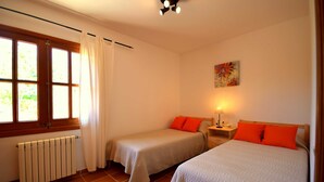 Une chambre avec deux lits, un radiateur, une fenêtre avec des rideaux, une table de chevet avec une lampe et un tableau au mur.