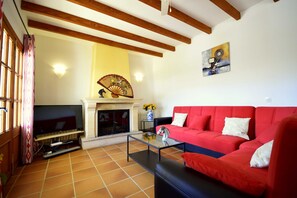 A living room with a red sofa, a glass coffee table, a fireplace, and a TV.