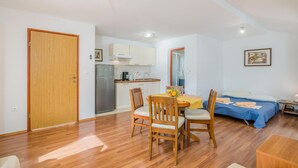 Un espace de vie compact comprenant un coin repas, une kitchenette et un lit.