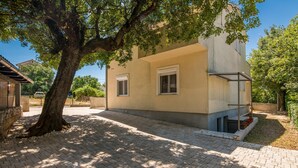 Un bâtiment moderne à deux étages, doté d’une allée pavée et d’un grand arbre à l’avant.