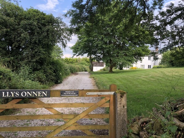 Ein Kiesweg führt zu einem weißen Haus mit einem Schild, auf dem 