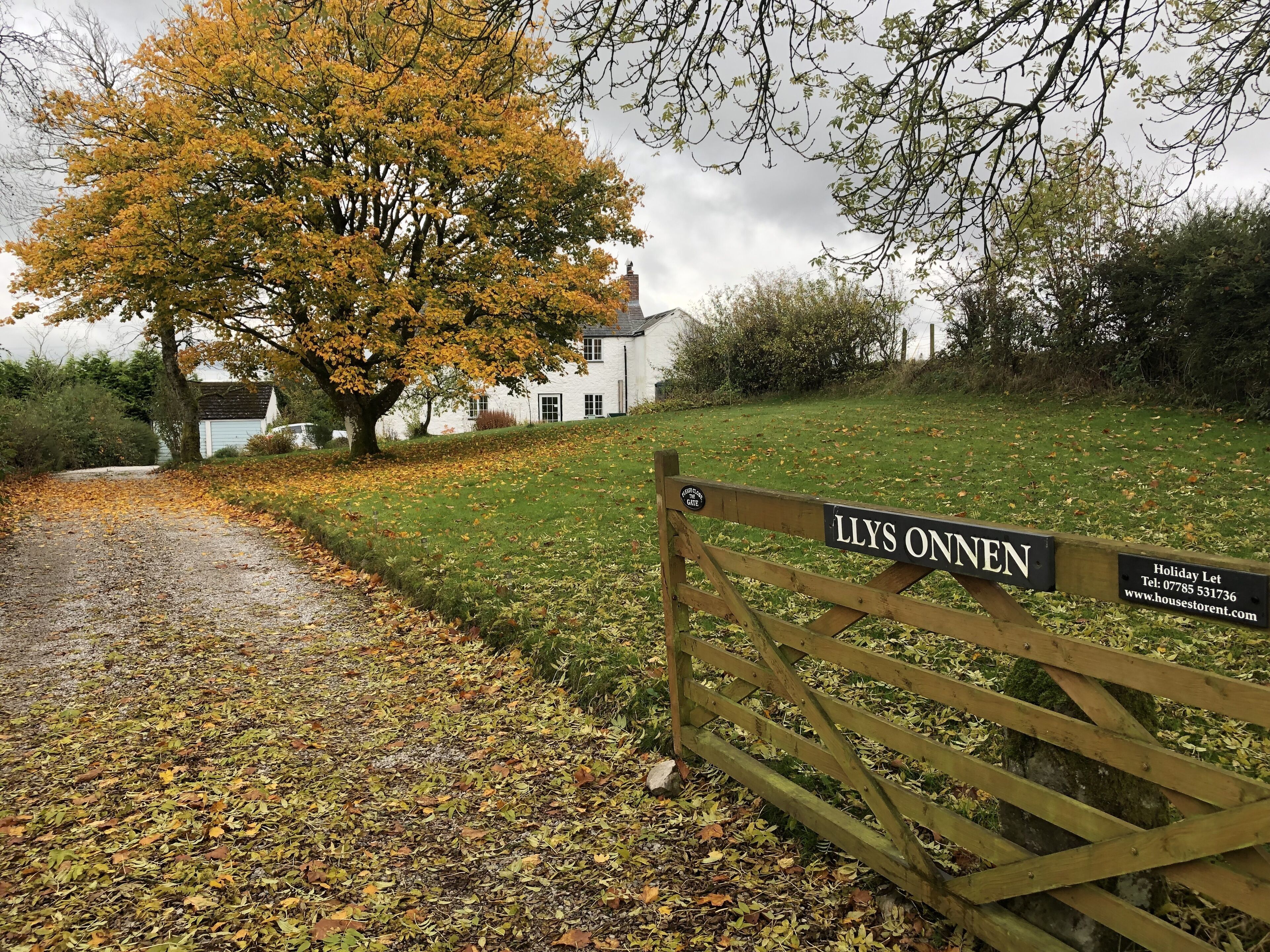 A wooden gate with a sign reading "LLYS ONEN" and a contact number.