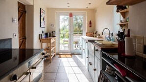 A kitchen with a large window, a wooden door, and a tiled floor.