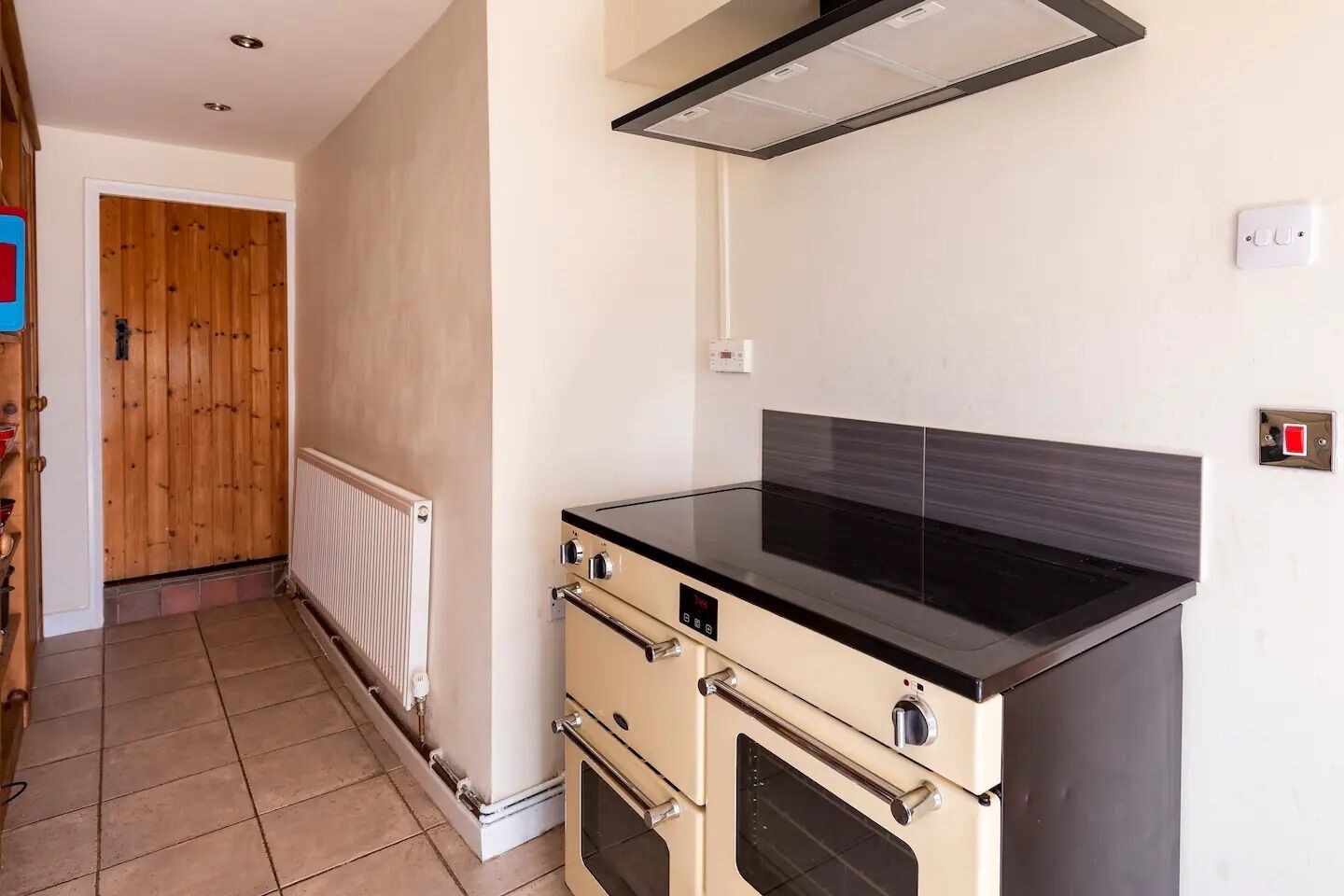 A compact kitchen with a black countertop, a built-in oven, and a wooden door in the background.