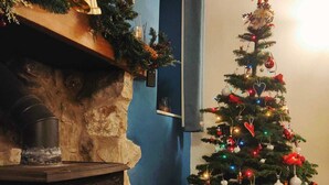 A cozy room with a fireplace, a decorated Christmas tree, and a basket of firewood.