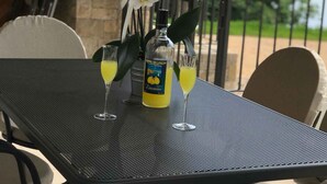 Un tavolo con una bottiglia di bevanda al limone e lime, due bicchieri e orchidee bianche.