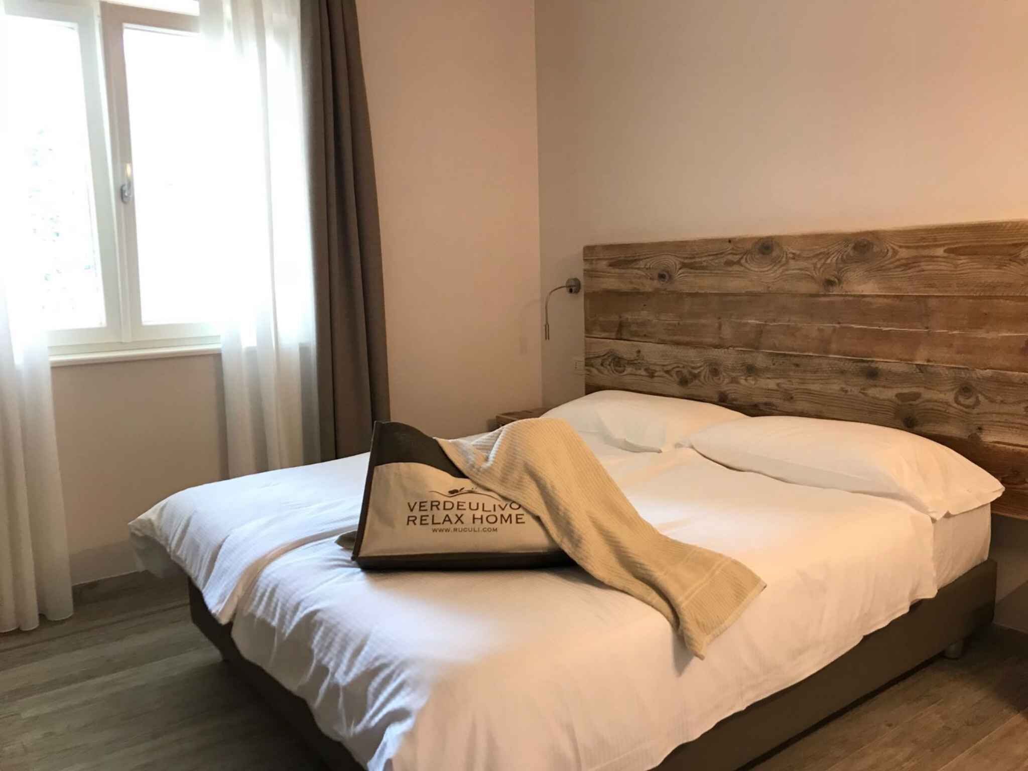 A neatly made bed with a wooden headboard, a pillow, and a blanket.
