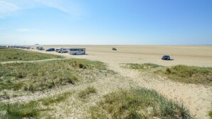 Uma praia com várias casas e carros estacionados na areia.