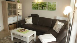 Ein Wohnzimmer mit braunem Sofa, einem weißen Couchtisch und einer Vitrine.