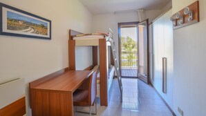 Una habitación con literas, un escritorio de madera, un cuadro y un balcón con vistas.