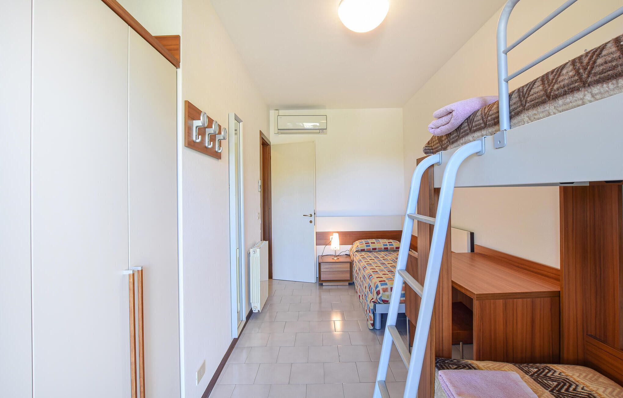 Una camera del dormitorio con letti a castello, una scala, un termosifone e una porta che dà su un'altra stanza.
