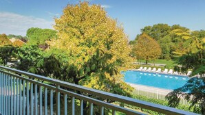 Una piscina con sillas de descanso, rodeada de abundante vegetación y árboles.