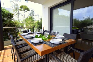 A dining table set for four with chairs, a bottle of wine, and a glass. - Villa Baulo Pleta 20227 - Villa Baulo Pleta (Can Picafort)