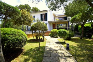 A modern two-story house with a stone pathway leading to the entrance, surrounded by well-maintained hedges and trees. - Villa Baulo Pleta 20227 - Villa Baulo Pleta (Can Picafort)