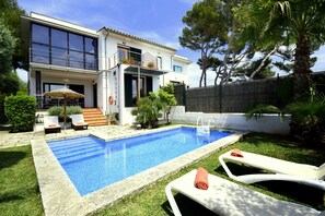 A modern house with a swimming pool, a balcony, and a well-maintained garden.