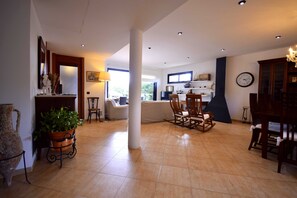 A spacious living area with a dining table, chairs, a fireplace, and a large window providing natural light.