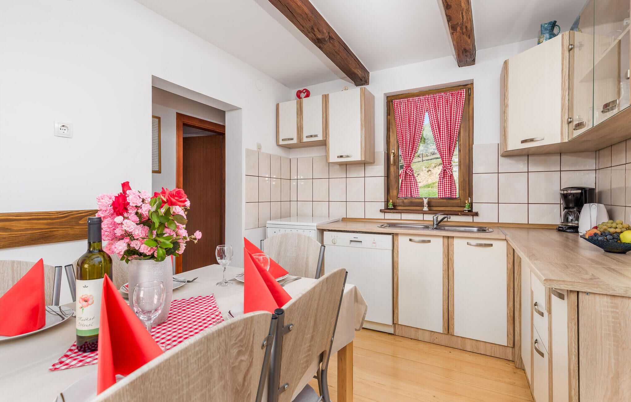 Een moderne keuken met witte kastjes, een houten aanrecht en een eethoek met een tafel, stoelen en een bloevas.